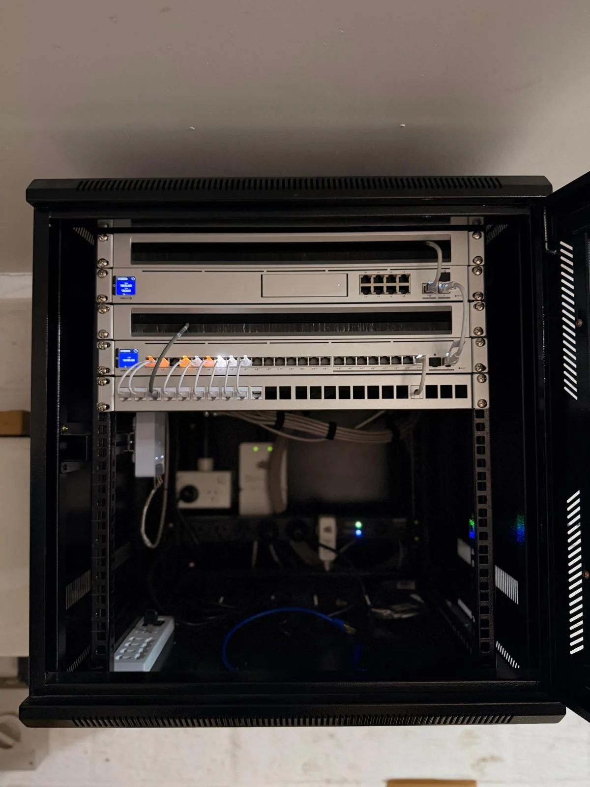 Full view of the wall-mounted network cabinet at the Waikiki home, with its door open